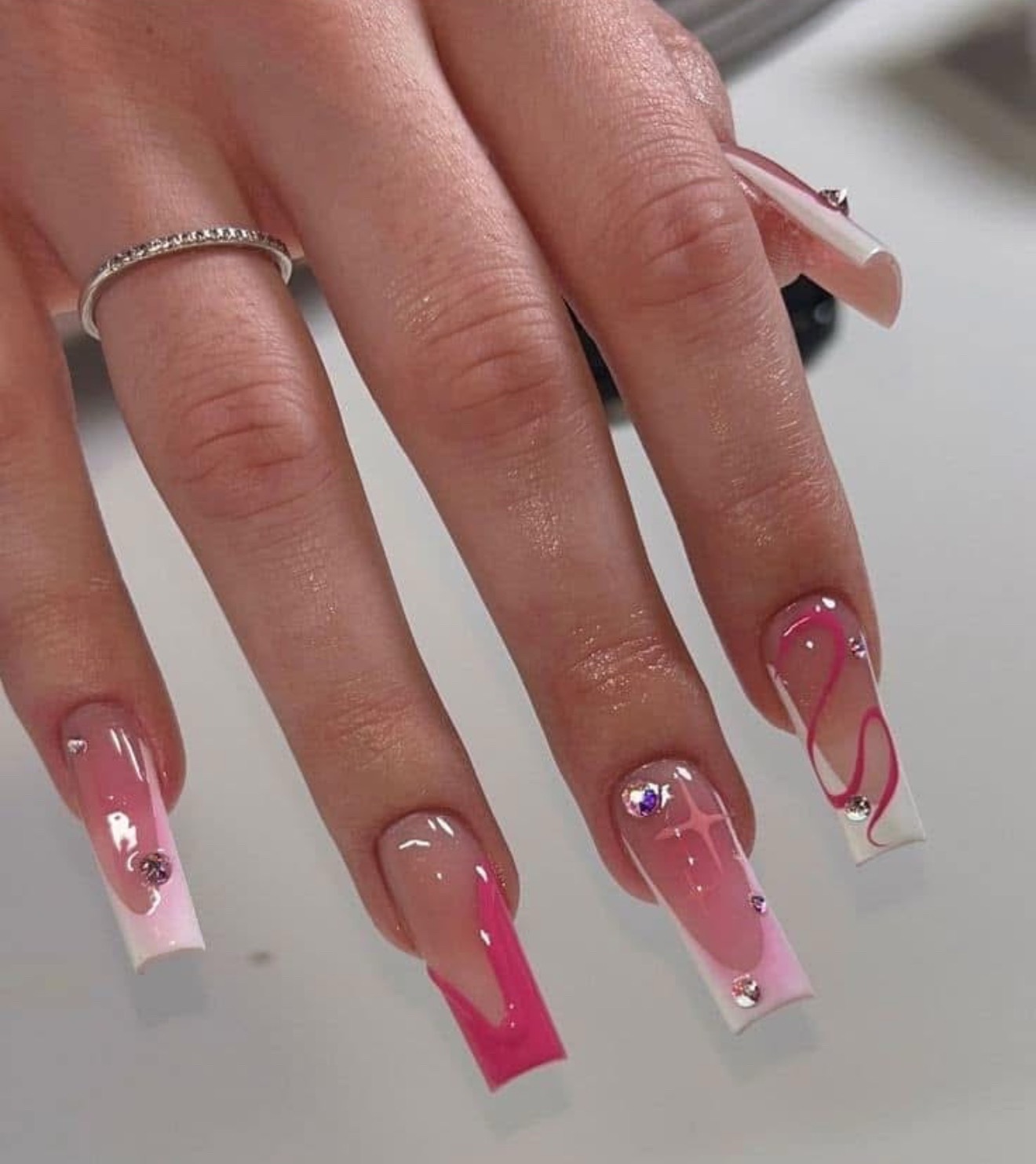 Pink and white nail art with rhinestone accents