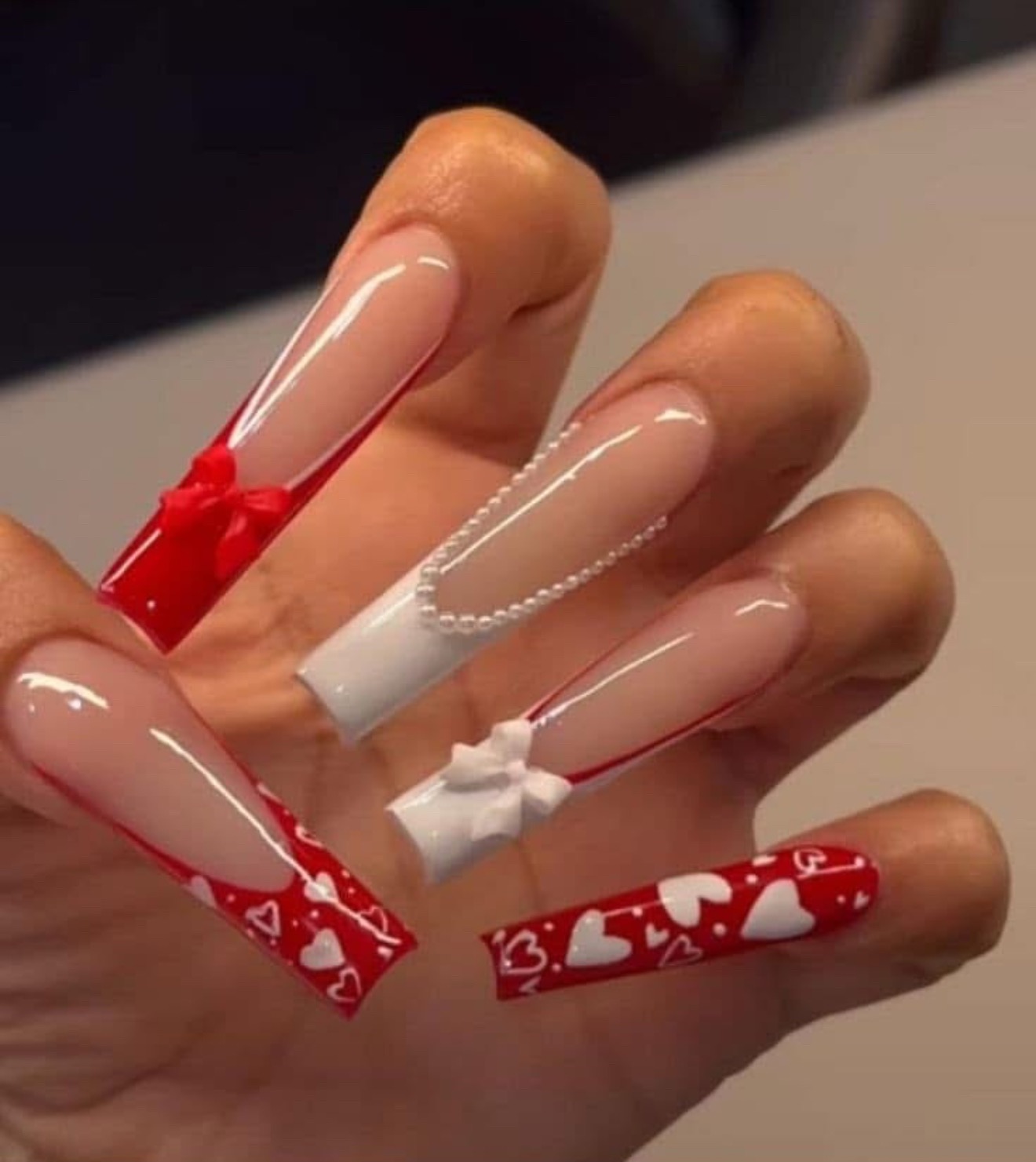 Red and white heart nail art with bow details